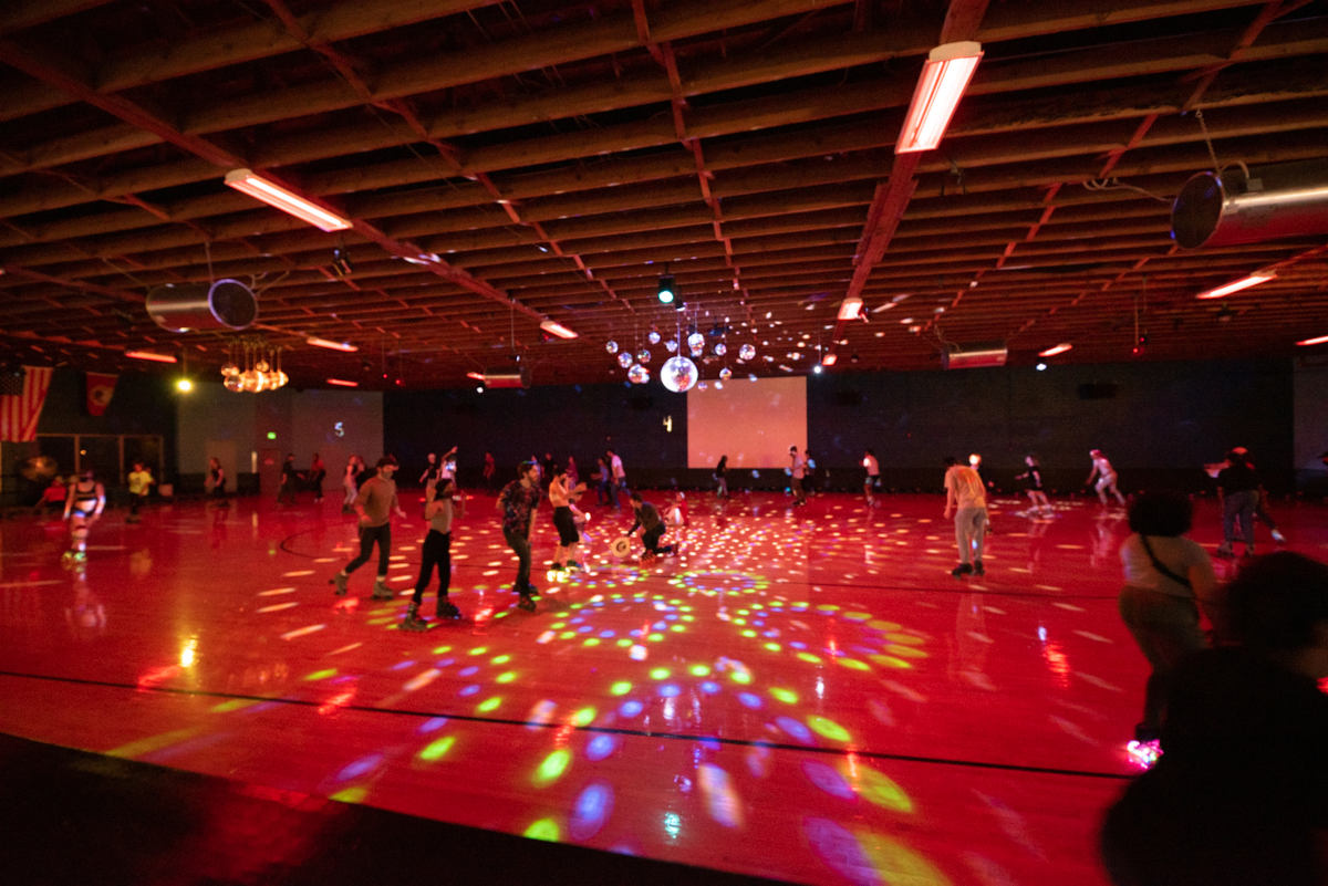 hardwood floor lit with multicolor disco lights and skaters skating
