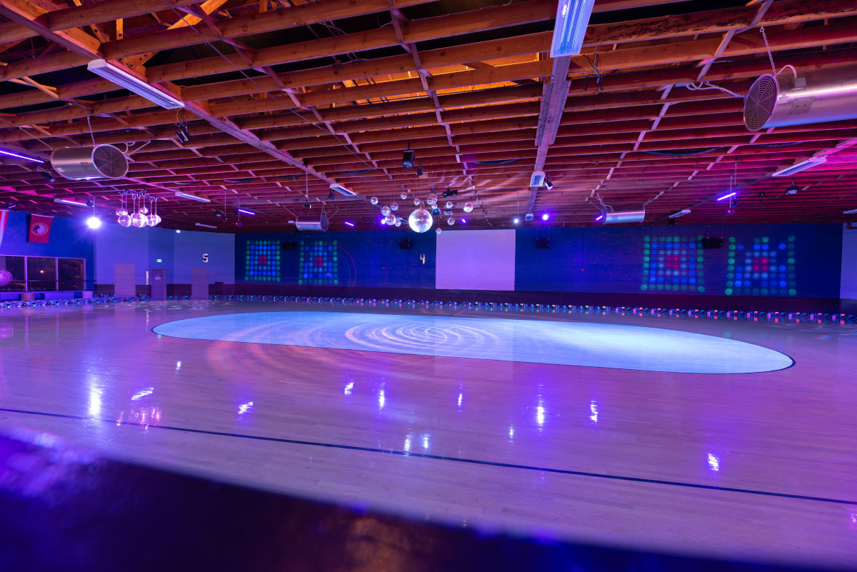 image of the the hardwood skate floor lit by blacklights with the center ring illuminated by blacklight reactive paint
